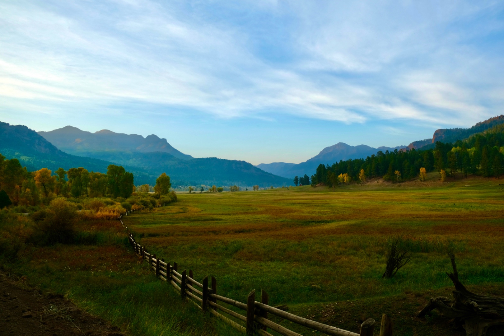 Mountain valley at dawn with wooden fence and autumn foliage