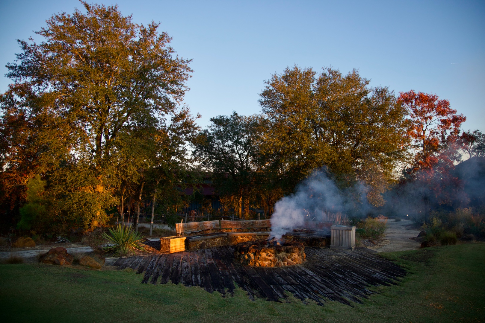 Rustic fire pit with smoke rising through golden hour light